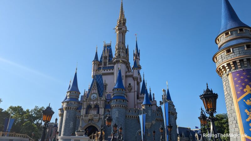 A blue and white castle with a clock tower in the middle of a park
